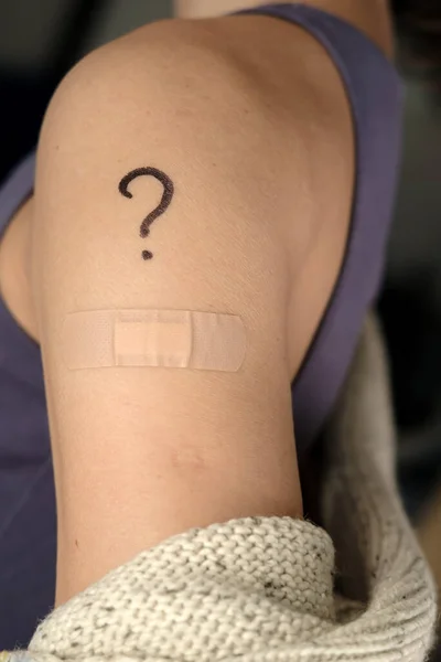 Épaule féminine avec un point d'interrogation et un bandage dessinés après la vaccination contre la coqueluche 19. Concept de sélection des vaccins. — Photo