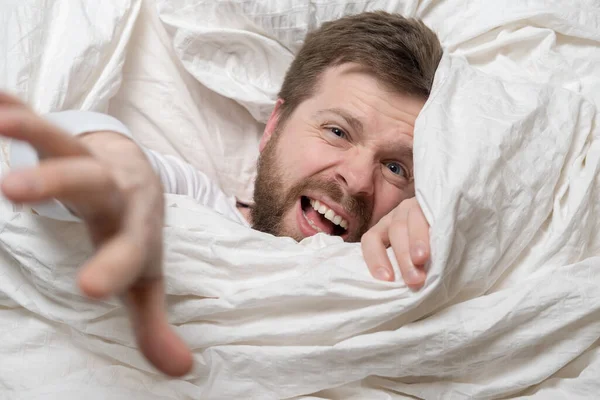 Un hombre asustado se despertó de una pesadilla, estiró la mano debajo de la manta, como si quisiera ser salvado. Primer plano. — Foto de Stock