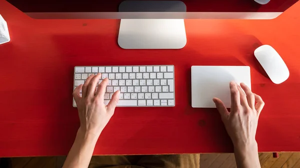 Weibliche Hände arbeiten mit einer Tastatur und einem Touchpad, eine Maus und ein Computer sind in der Nähe. Fernbedienung. Zeitgemäßer Arbeitsplatz. — Stockfoto