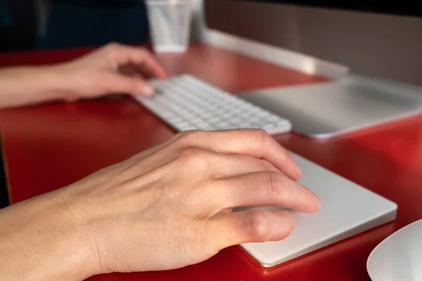 Weibliche Hände arbeiten mit einer Tastatur und einem Touchpad, ein Computer ist in der Nähe. Fernbedienung. Zeitgenössischer Arbeitsplatz und Lebensstil. — Stockfoto