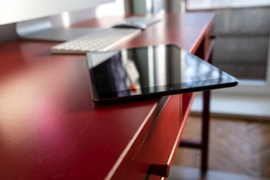 Tablet tehlikeli bir şekilde masanın kenarında duruyor ve düşebilir. Alete karşı dikkatsiz tavır. Yakın plan..