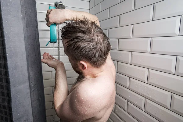 Běloch si nalije šampon do dlaně a stojí ve sprše pod proudem vody. Hygienický koncept. — Stock fotografie