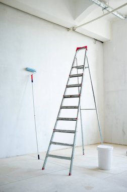 Stepladder, kapalı plastik bir kova boya ve boya silindiri, odada. Onarım için hazırlık.