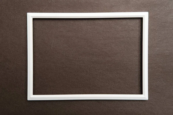 Marco blanco rectangular en blanco sobre fondo marrón texturizado. Copiar espacio. Vista superior. —  Fotos de Stock