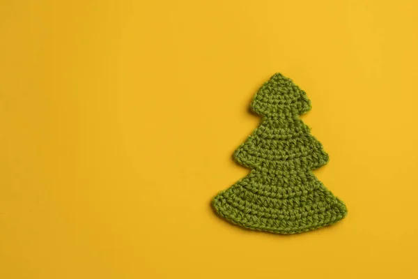 黄色の背景に新年とクリスマスの象徴である自家製のクリスマスツリーを編んだ。コピースペース。休日と魔法の概念。トップ表示. — ストック写真