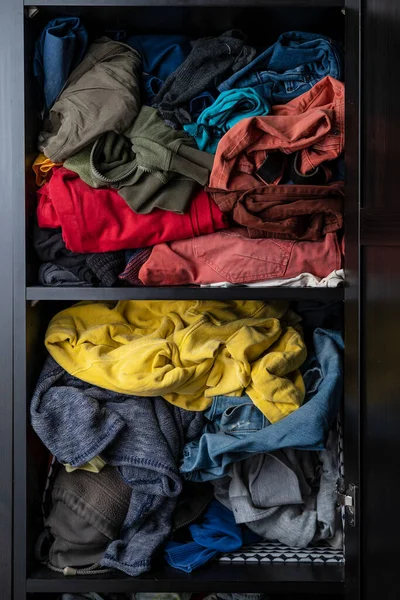 Parlak renkli kıyafetlerin çeşitliliği bir dolabın rafında gelişigüzel yatıyor.. 