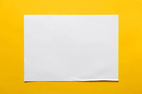 Quadro de uma folha de papel branco em um contexto amarelo. Espaço para cópia. Vista superior. — Fotografia de Stock