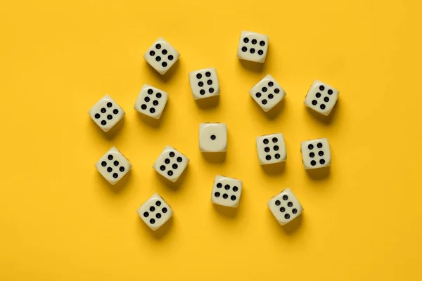 Dice on a yellow background, many sixes surrounded one unit. Top view. — Stock Photo, Image