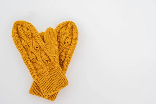 Knitted yellow mittens lie on pure white snow on a cloudy winter day. Copy space. Top view. — Stockfoto