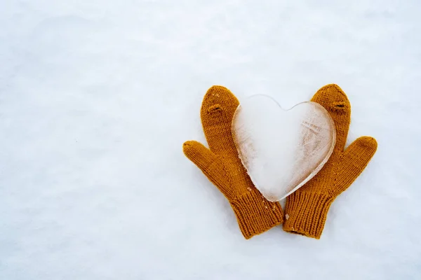 Simbol hati cinta, terbuat dari es, pada sarung tangan kuning hangat rajutan, pada salju. Hari Valentine. Salin ruang. Konseptual. Tampilan atas. — Stok Foto