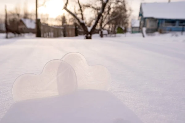 Two hearts - a symbol of love, made of ice, in a snowdrift, in a village courtyard. Valentines Day. Romantic concept. Copy space. — Stok fotoğraf