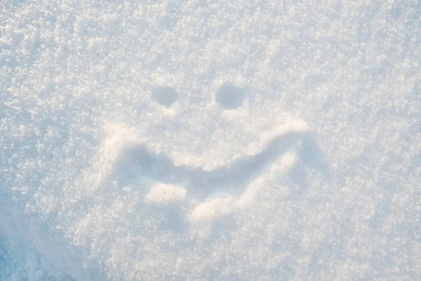 Cute smiley face drawn on the snow on a sunny winter day. Top view. — Stockfoto