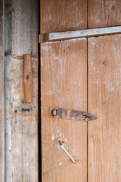 Holzverschluss und Vorhängeschlaufe aus Metall an bemalter Planktür, im Freien. Landhausstil. — Stockfoto