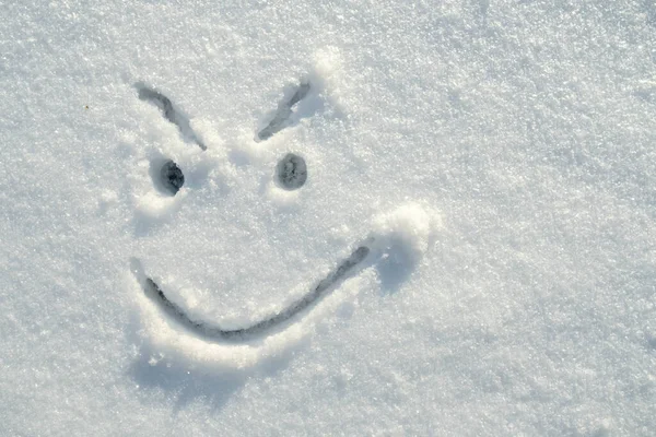 Πρόσωπο ενός ύπουλου, θυμωμένου, χαμογελαστού, ζωγραφισμένου στο χιόνι μια ηλιόλουστη χειμωνιάτικη μέρα. Αντιγραφή χώρου. Άνω όψη. — Φωτογραφία Αρχείου