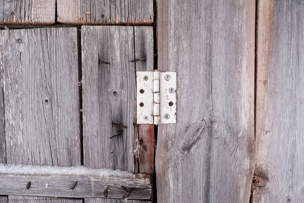 Stary zawias na drewnianych drzwiach stodoły z zardzewiałymi gwoździami wystającymi z desek na wsi. Streszczenie tła. — Zdjęcie stockowe