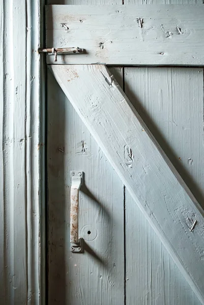 Metallverriegelung und Griff an einer geschlossenen, lackierten Holztür, aus der Nägel ragen. Landhausstil und Lebensstil. — Stockfoto