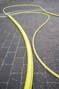 Sarı yangın hortumu kaldırımlı bir yolda, açık havada. İtfaiye ekipmanı. 