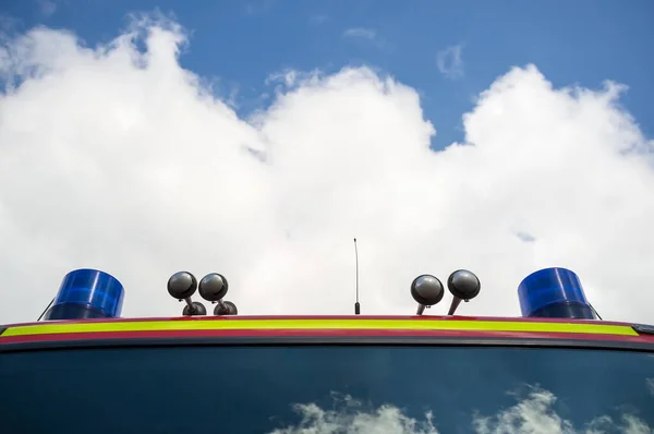 Motor de bomberos con lámparas de señal y una sirena, contra el cielo azul y las nubes blancas. Concepto de rescate y seguridad. Copiar espacio. — Foto de Stock