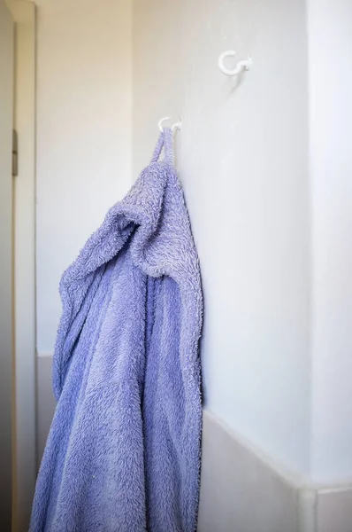 Fioletowy szlafrok wiszący na haku na ścianie łazienki. Styl życia. — Zdjęcie stockowe