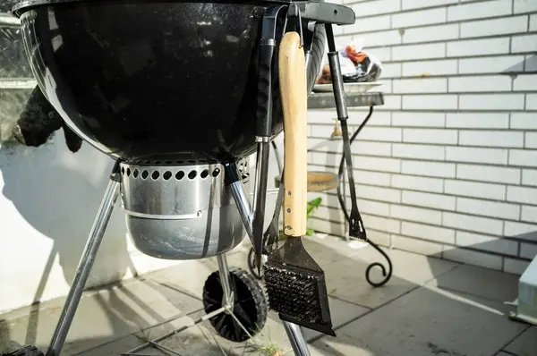 Ein moderner Grill mit einer Reinigungsbürste steht im Hof eines Hauses. Nahaufnahme. — Stockfoto