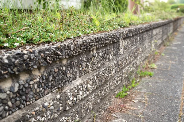 小さな石で作られた古い美しいフェンスと地方の町の通りにコンクリート. — ストック写真