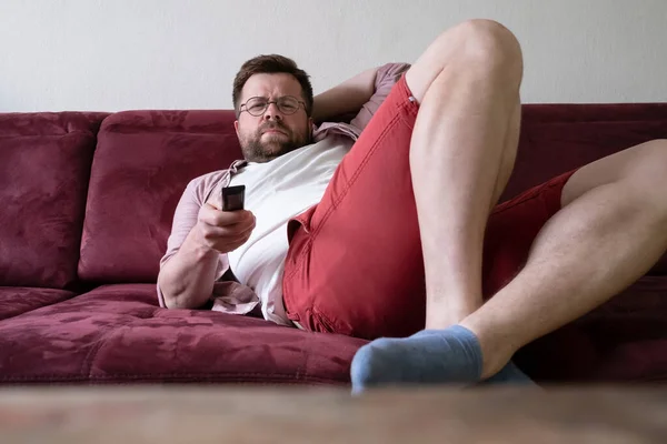 Tired Frowning Man Holds Remote While Lying Sofa Watching Movies — Stock Photo, Image