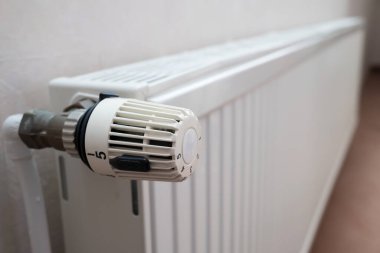 Termostatlı radyatör ve düğmeyi çevirme ve ısıyı düşürme yeteneği. Kriz kavramı ve ısıtma maliyetlerinde artış. Yakın plan..