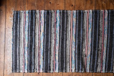 Ahşap zeminde çok renkli bir halı var. Kapalı alanda, arka planda. Uzayı kopyala Üst görünüm.