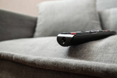 TV kumandası kazara kanepenin kenarına bırakılmış ve düşebilir. Olaylara dikkatsiz yaklaşma kavramı. Yakın plan..
