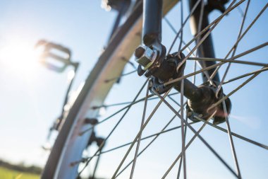 Bir yaz günü, bir çayırda, güneşin ve mavi gökyüzünün arkaplanına parkedilmiş bir bisikletin yakın çekim detayları. Sağlıklı ve aktif yaşam tarzı konsepti. Alt görünüm.