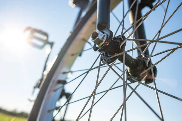 Bir yaz günü, bir çayırda, güneşin ve mavi gökyüzünün arkaplanına parkedilmiş bir bisikletin yakın çekim detayları. Sağlıklı ve aktif yaşam tarzı konsepti. Alt görünüm.