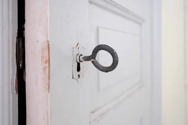 白い木製のドアの鍵穴に挿入されたヴィンテージの大きなキーのクローズアップ — ストック写真