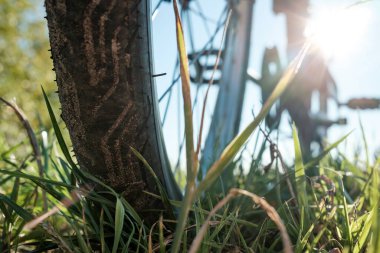 Bir yaz günü, bir çayırda, güneşin ve mavi gökyüzünün arkaplanına parkedilmiş bir bisikletin yakın çekim detayları. Sağlıklı ve aktif yaşam tarzı konsepti. Alt görünüm.