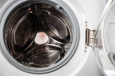 Yıkandıktan sonra kapısı açık olan boş bir çamaşır makinesi, çamaşır makinesinin içini kurutmak ve havalandırmak için. Yakın plan.. 