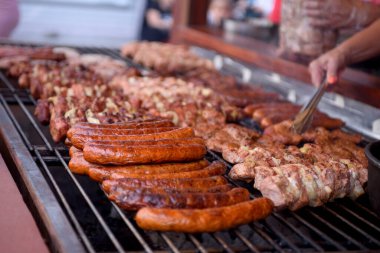 Cooking meat dishes in a summer restaurant on the street. Assorted delicious grilled meat with vegetables over charcoal barbecue.