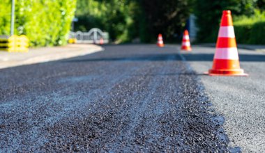 Construction cones marking part of road with a layer of fresh asphalt.	