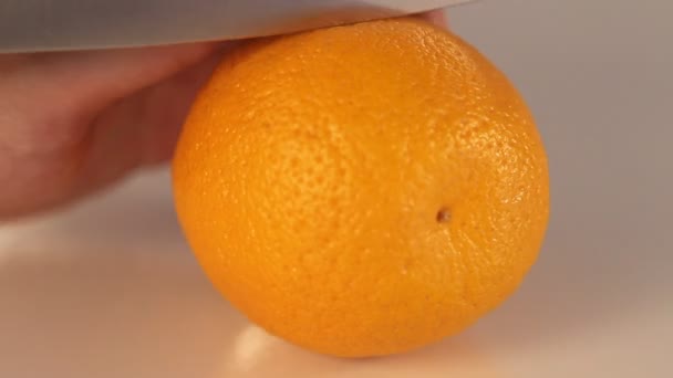 Человек режет свежий апельсин на кухне — стоковое видео