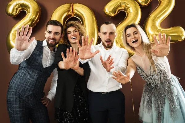 2022年の到来を祝う美しいよく服を着たパーティーの人々のグループ茶色の背景に金色の風船 — ストック写真