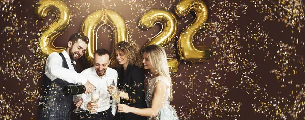 2022年の到来を祝うパーティーの人々のグループ黄金の風船と秋のコンフェッティは輝くワインを飲む — ストック写真