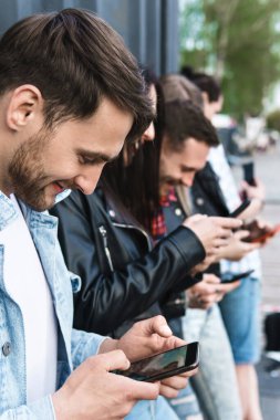 Bir grup genç ve şık arkadaş gerçek iletişim yerine akıllı telefonları kullanıyor.