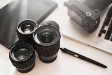 Modern ekipmanlı fotoğrafçı işyeri. Aynasız kamera, dizüstü bilgisayar ve asal lensler.