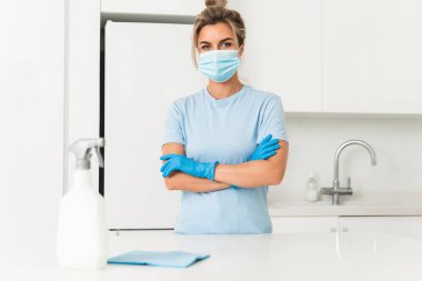 Temizlik sırasında koruyucu maske ve eldiven takan genç bir bayan işçi.