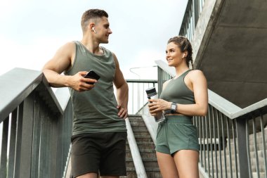 Spor yapan genç çift dışarıda spor yaptıktan sonra dinleniyor.