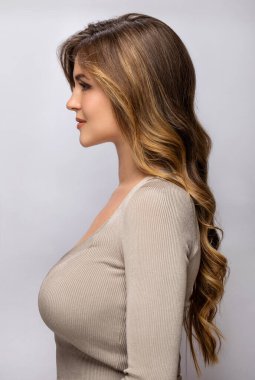 Gri arka planda kıvırcık saçlı güzel bir kadının portresi.