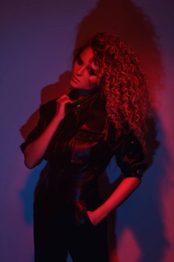 Genç ve seksi bir kadın şık Afro saç stili deri motosiklet giyip renkli neon ışıkta poz veriyor.