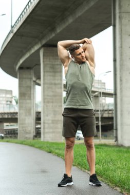 Yakışıklı kaslı adam dışarıda spor yapmadan önce ısınıyor.