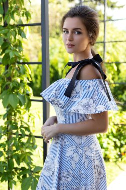 Bahçede güzel elbiseler giyen muhteşem bir kadının portresi.