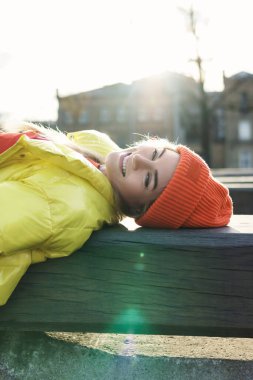 Sarı puf ve turuncu örgü şapka giyen şık bir kızın portresi. 