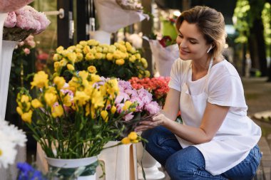 Young and beautiful woman florist working in her little flower shop clipart