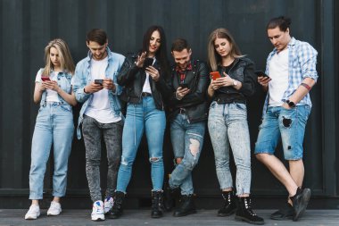 Bir grup genç ve şık arkadaş gerçek iletişim yerine akıllı telefonları kullanıyor.